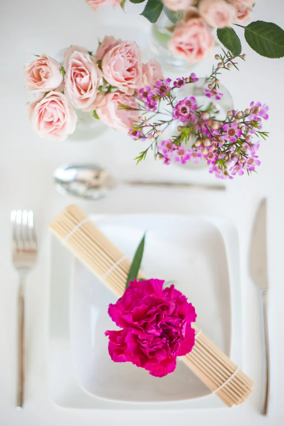 Prato decorado com flor e talheres envoltos em laço