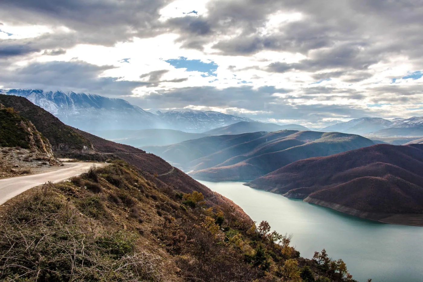 Estrada de montanha contornando um lago ao entardecer