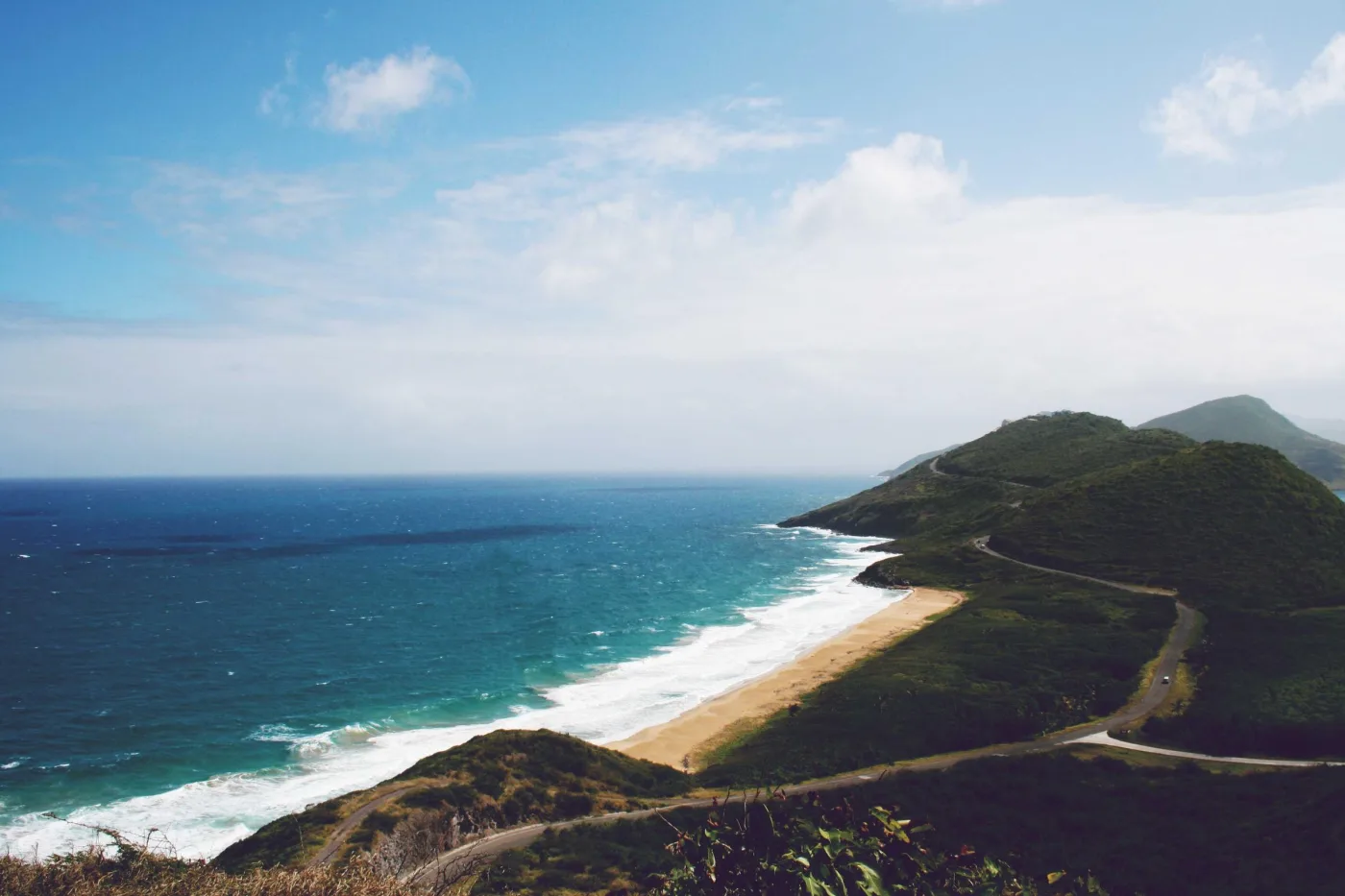 Praia curva e estrada costeira entre morros