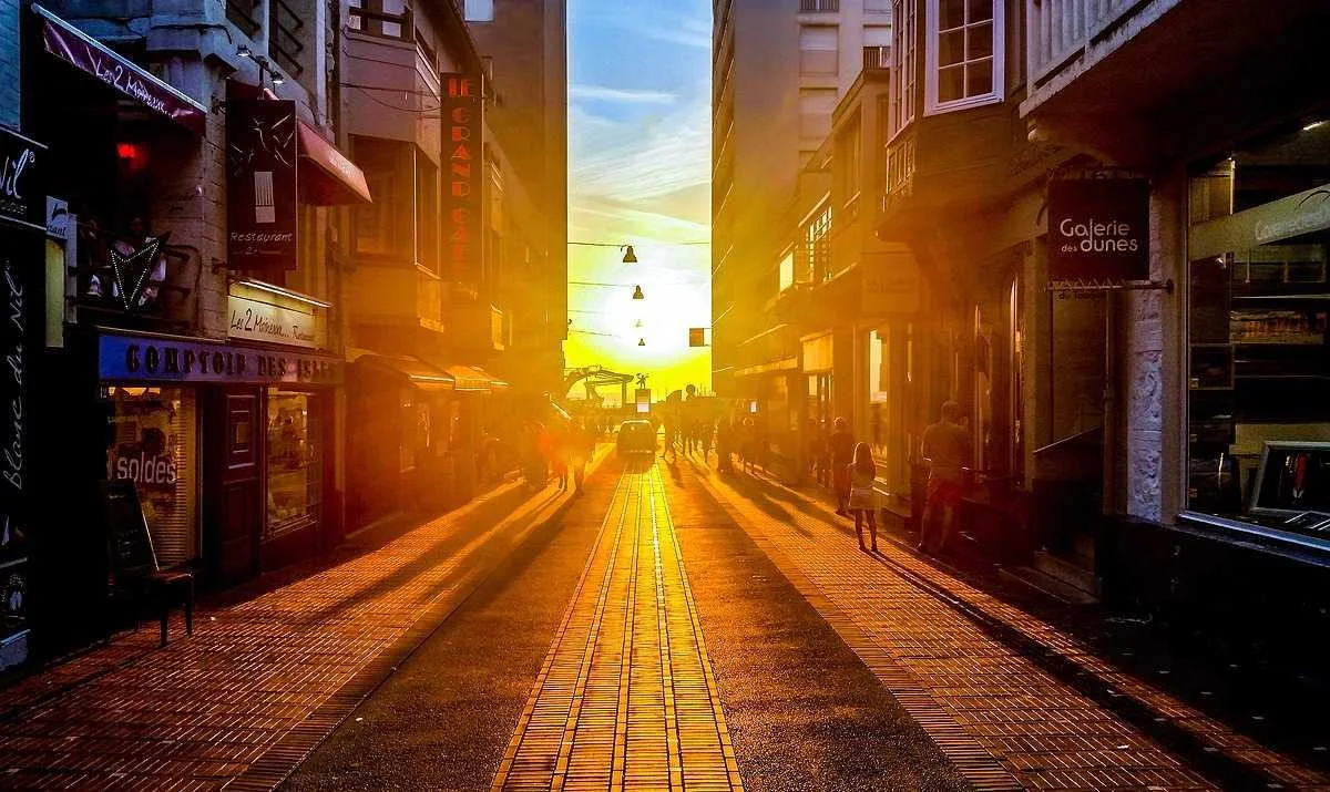 Rua com o sol se pondo exatamente no fim dos prédios