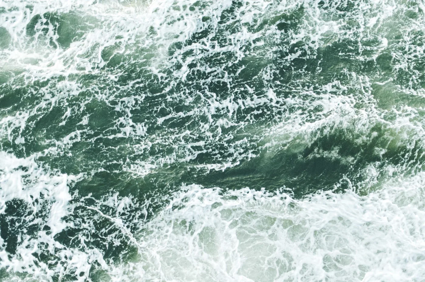 Espuma branca de ondas sobre mar verde, vista de cima